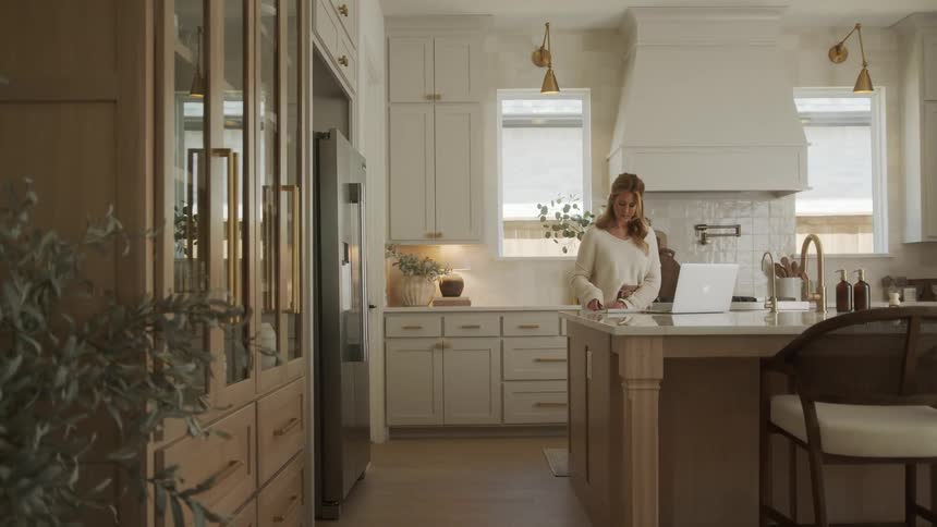A woman is using her laptop in the kitchen