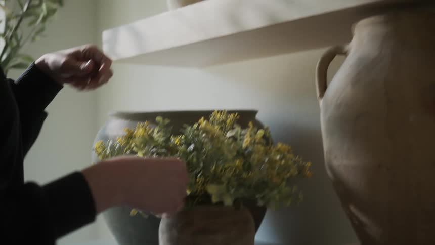 Woman arranging decorative vases in moments indoors