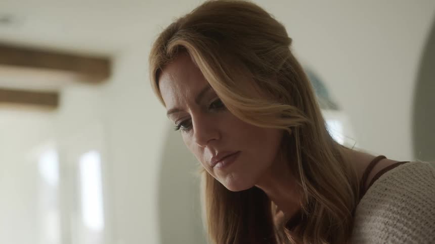 Portrait of a blonde woman looking down in an indoor space of the house concentrated