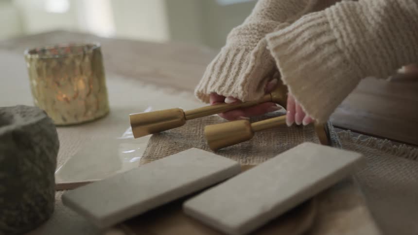 Female designer wearing sweater places interior design elements on table together
