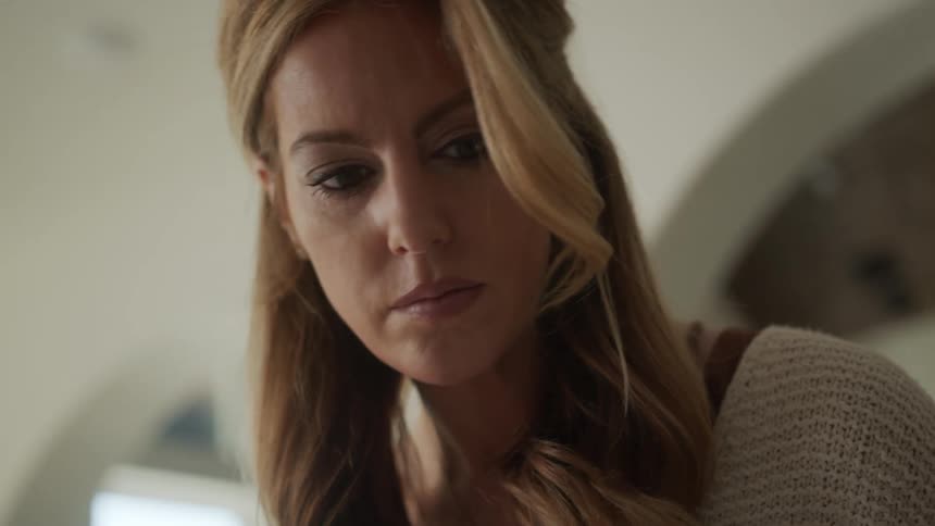 Portrait of a blonde woman indoors looking down and thoughtful