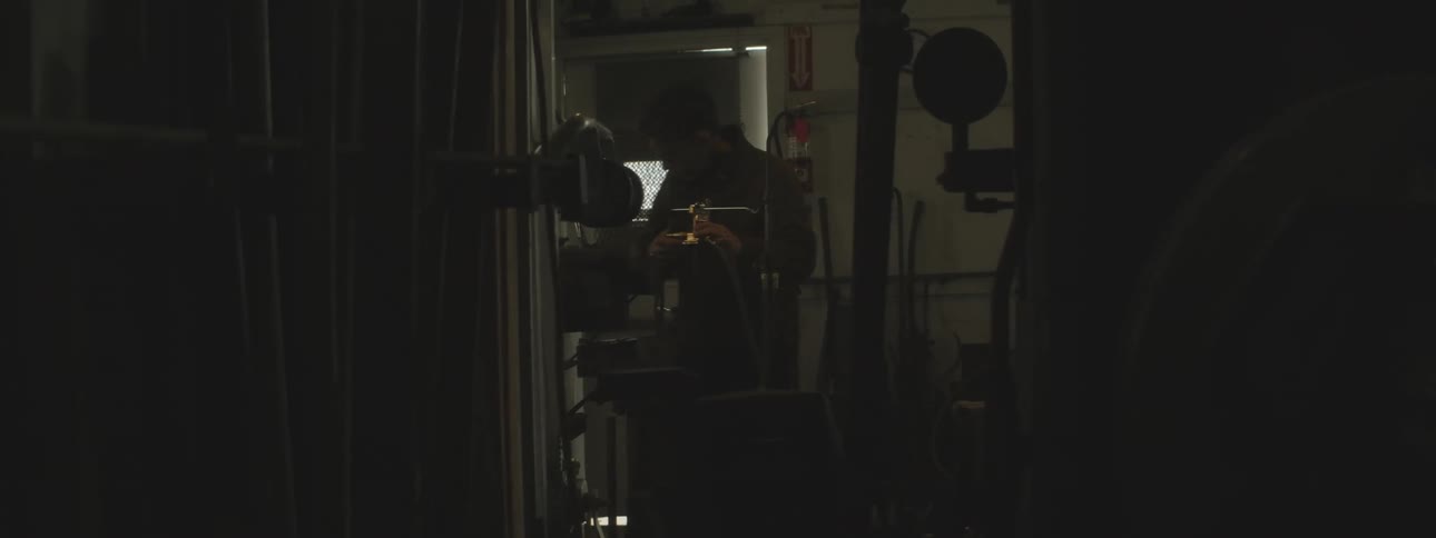 Man adjusts gauge and hose on equipment in utility room