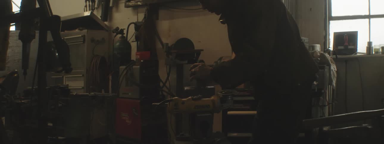 Man putting a part into a crank in a welding shop