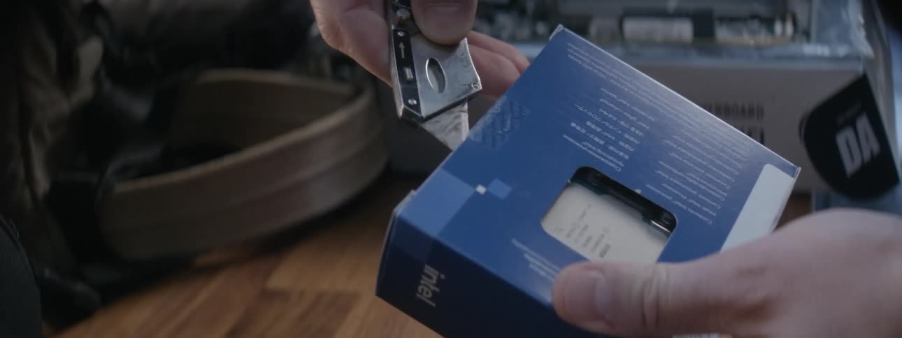 A person using a blade to cut open a computer processor packaged in a box