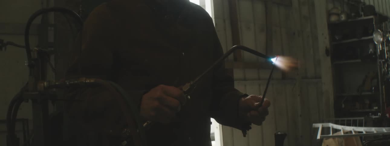 A worker heats a piece of metal with a torch