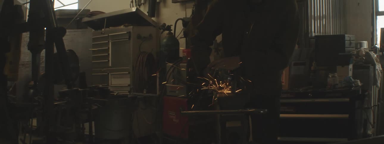 Man in a garage clenching a metal