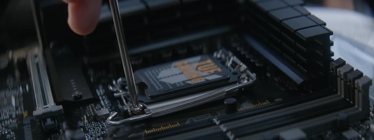An employee tightens a screw on a motherboard