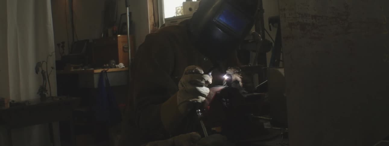 A welder is welding metal in the shop