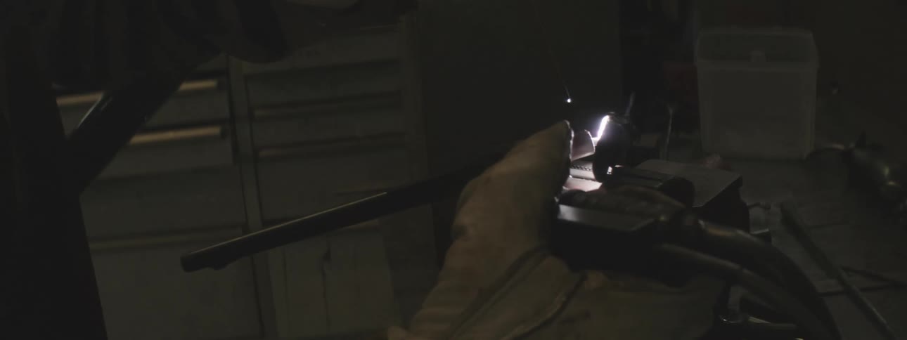 A person is welding in the dark shop