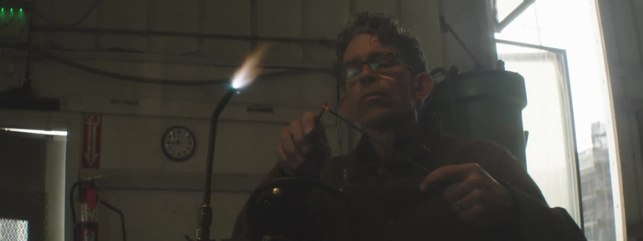 A tradesman heats metal with a torch in a shop