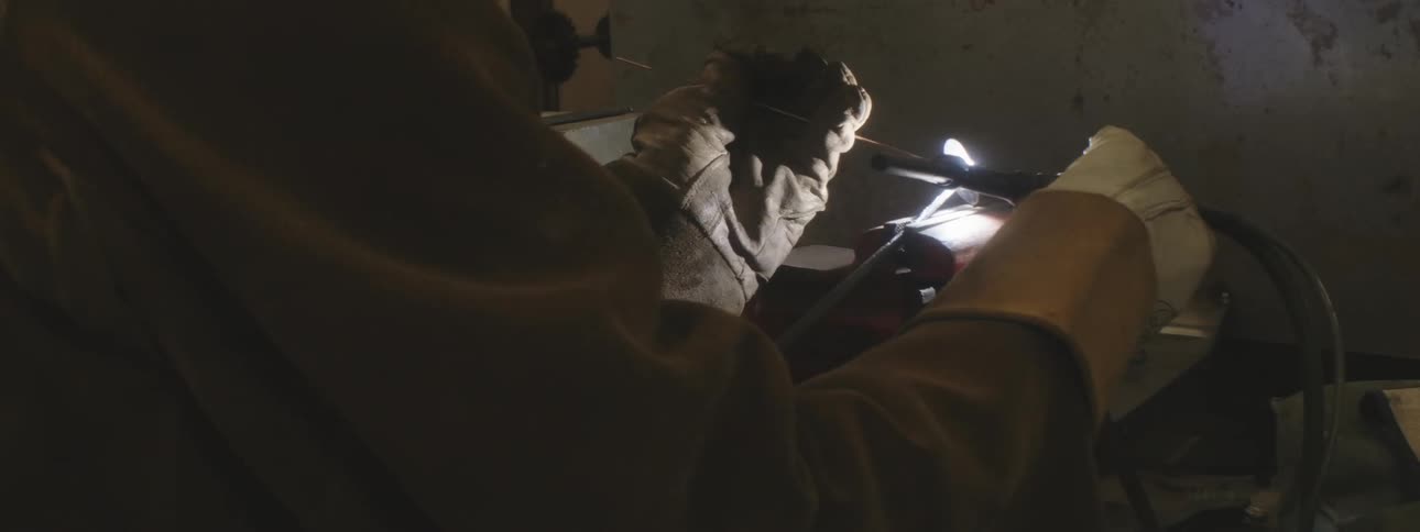 Person wears heavy duty gloves and welds a hose piece