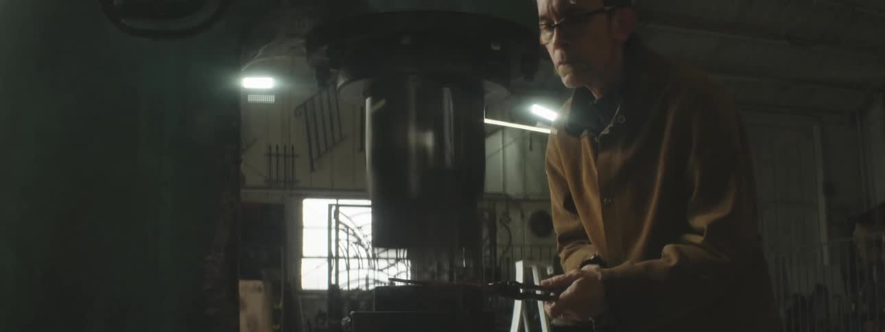 A worker shapes metal with a press