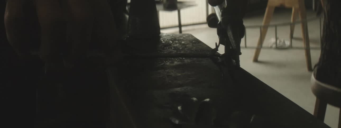 Closeup of a mans hands with tools shaping an iron rod