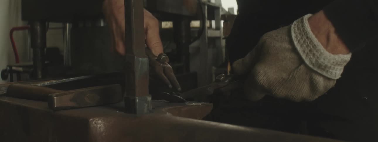 A blacksmith is using tools on metal