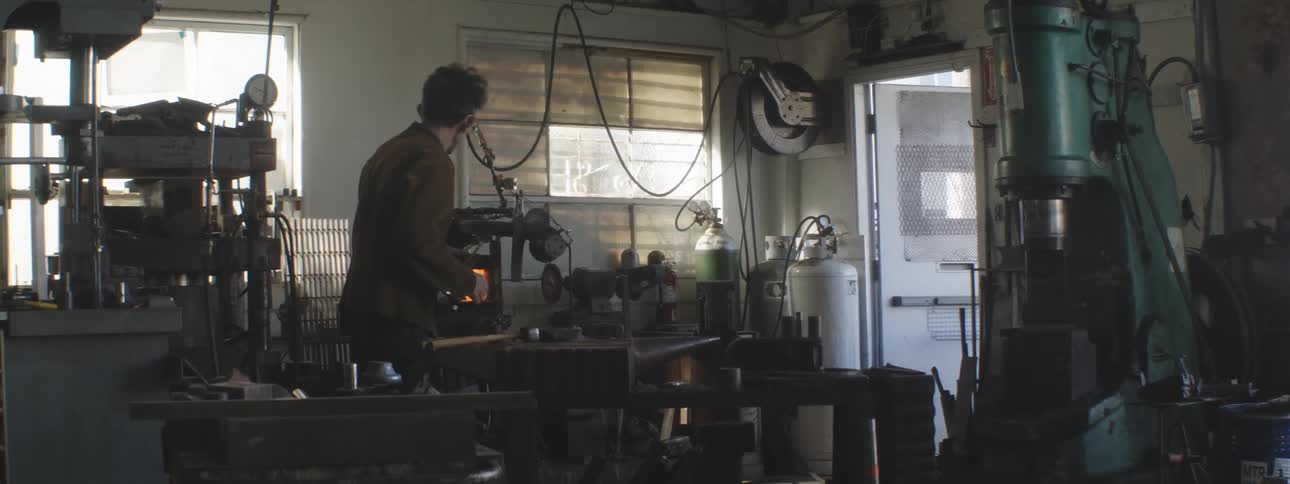 A man using a small metalworking furnace in the workshop