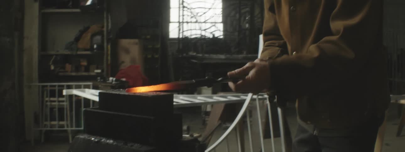 A man is hammering hot metal with a machine