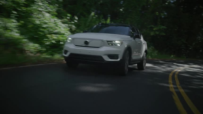 A car drives down a road in a forest