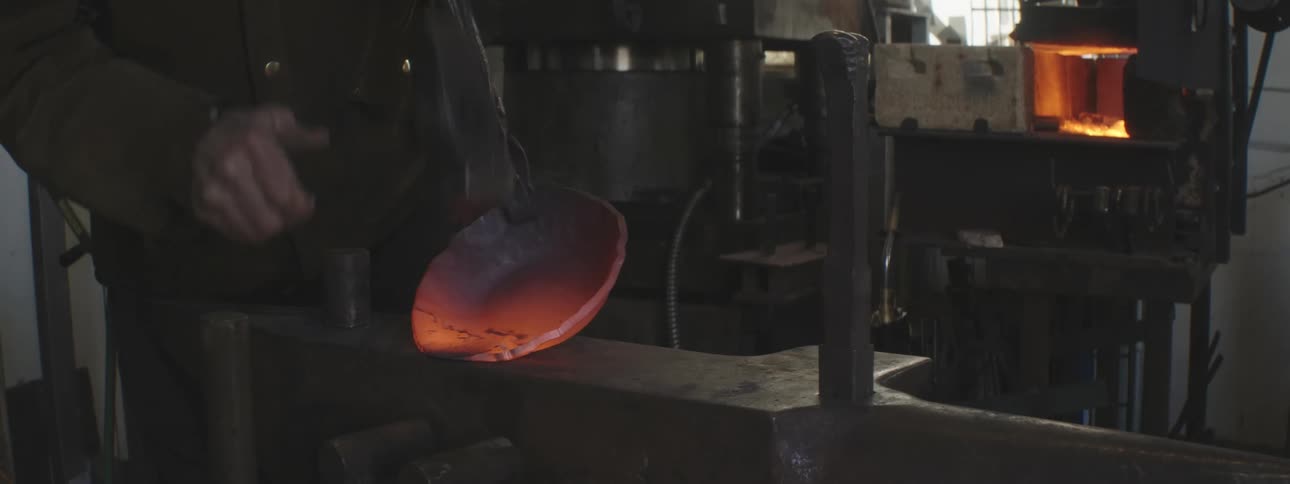 A blacksmith hammers hot metal from the forge