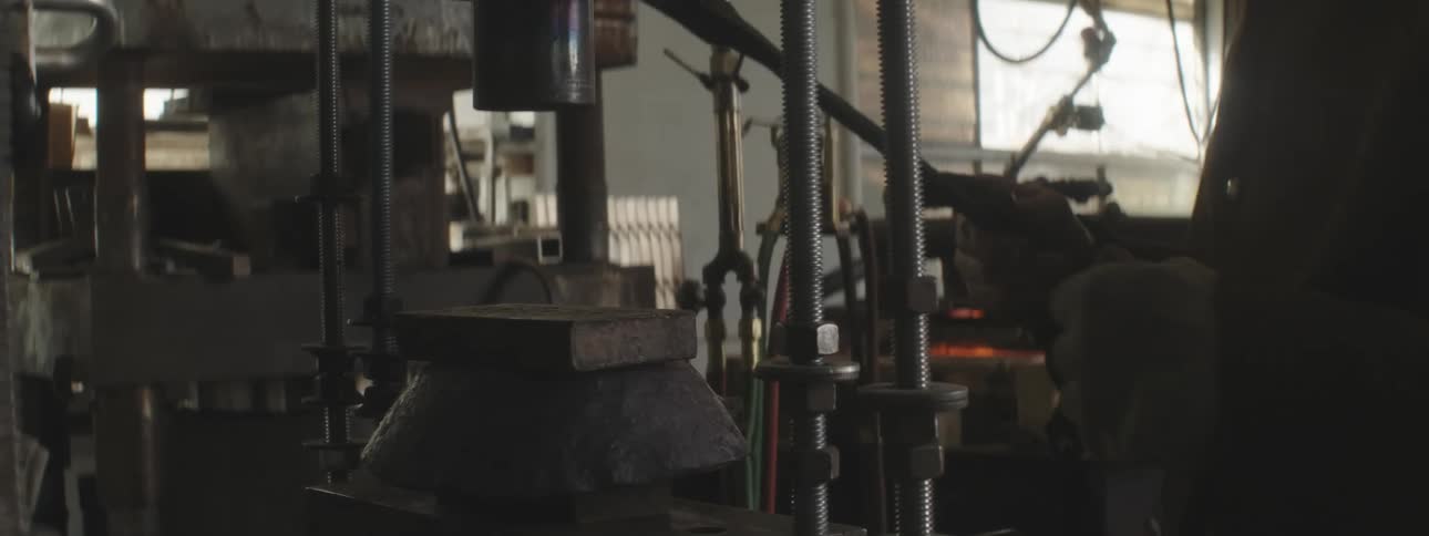 A man hammers metal on the machine