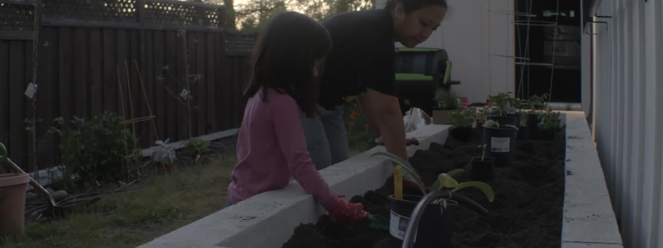 A man tending the garden in the backyard with his daughter