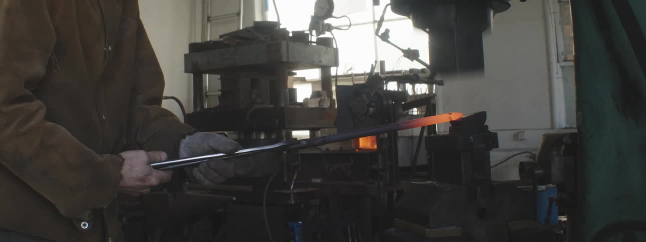 A man uses an automatic press to shape hot metal