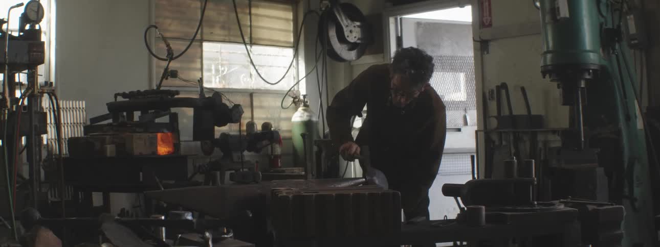 A worker hammers a piece of metal