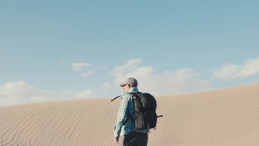 A man backpacks through Mesquite dunes in Death Valley National Park