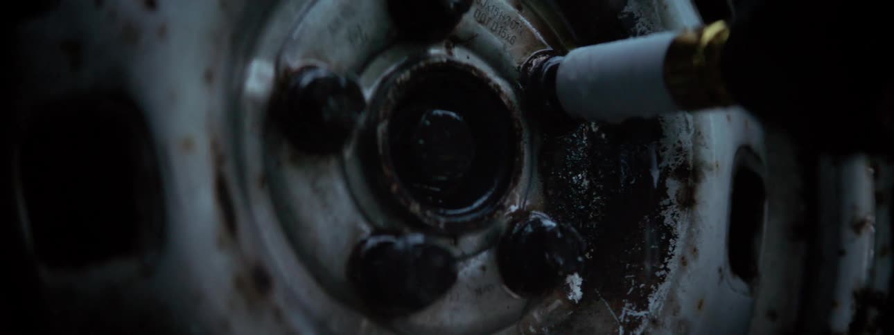 A mechanic tightens the screws on a tire with a power tool