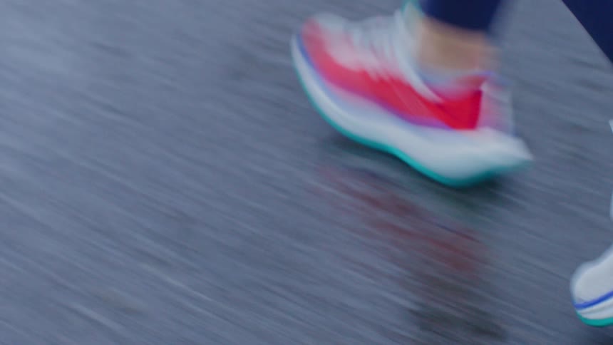 Closeup of a persons sneakers running on a wet street