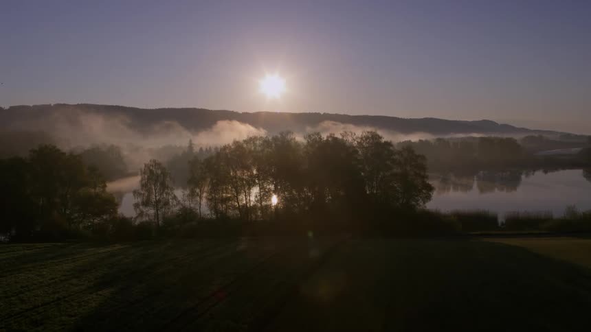 Aerial of rural areas with sunlight reflected on the lake during the early morning