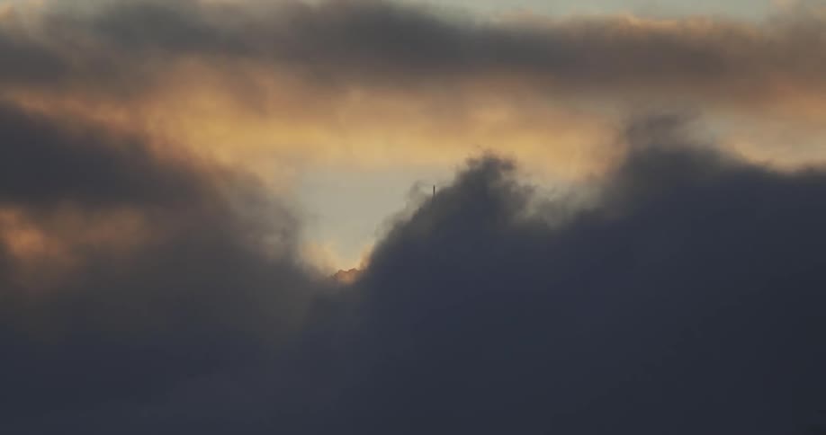 The rounded dome of a building is barely visible behind the passing clouds