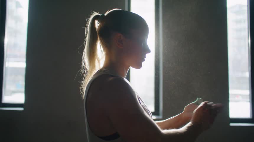 A woman puts chalk on her hands in the gym