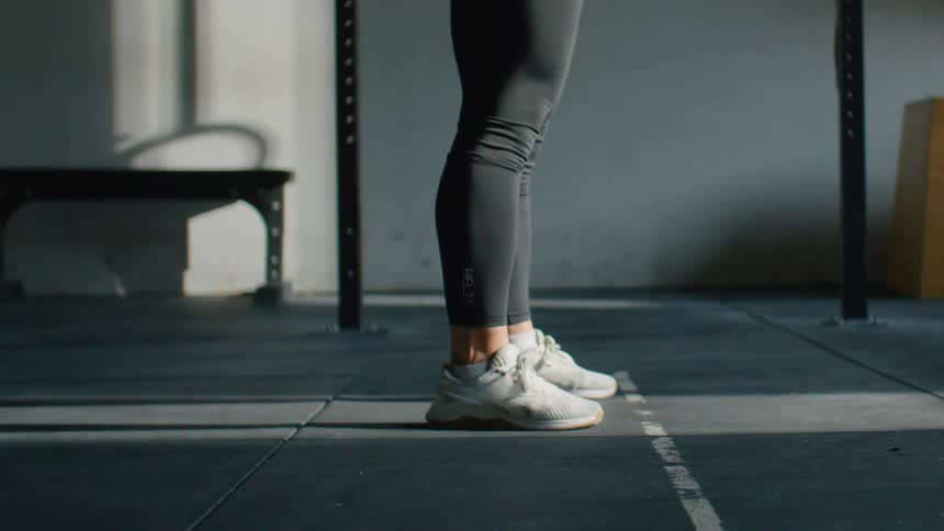A female lifts a large bar with weightlifting plates on it before dropping it