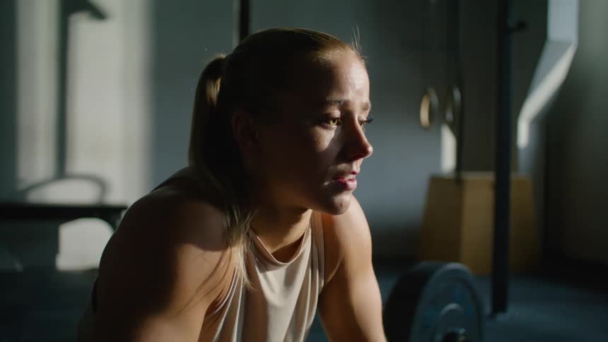 A young weight lifter breathing heavily sitting at a gym