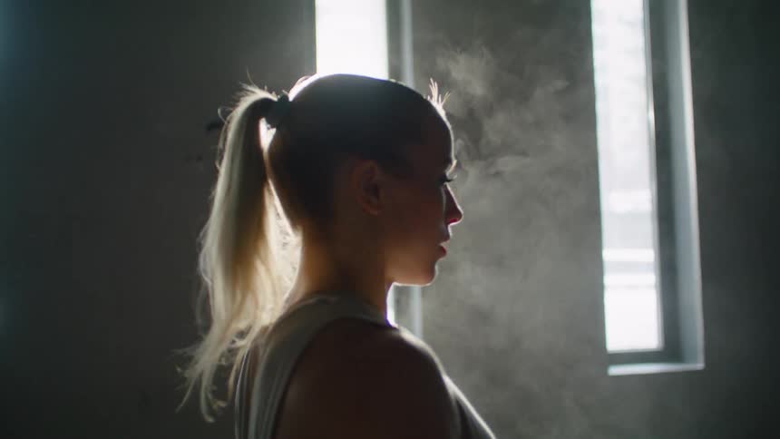 Framed by sunlight coming in from a window an athlete claps her hands releasing dust preparing to begin exercising