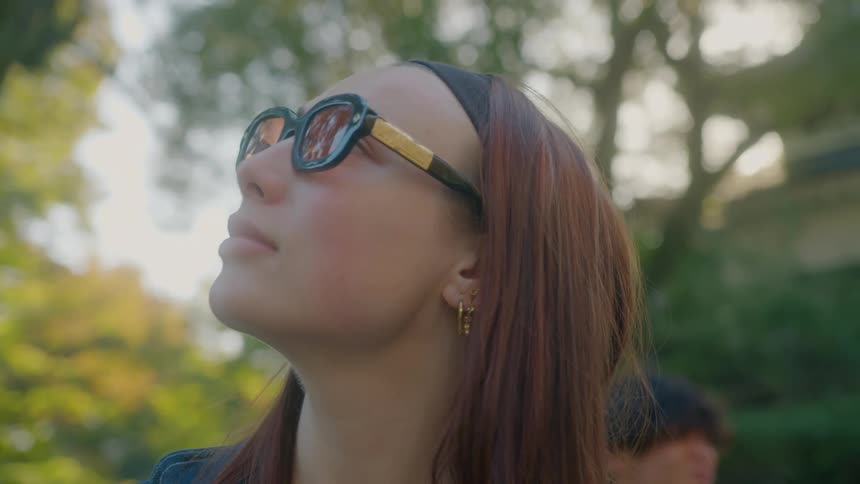 A womans face wearing glasses and she is looking from one side to the other