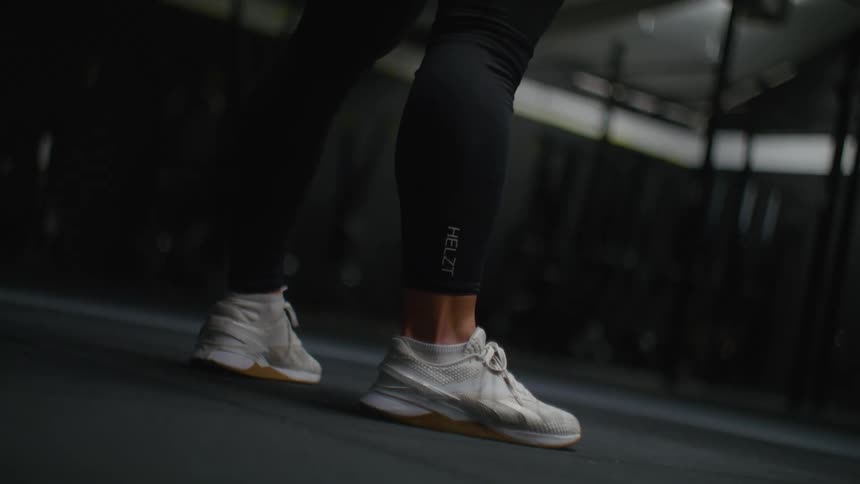 Person swinging a kettle bell between their legs in a dimly lit gym