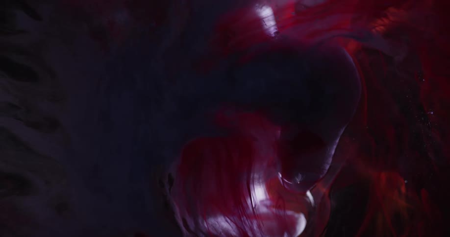 A smoky abstract object of black and red color is contracting