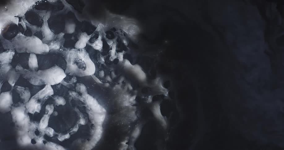An abstract liquid has a white expansive foam on its surface
