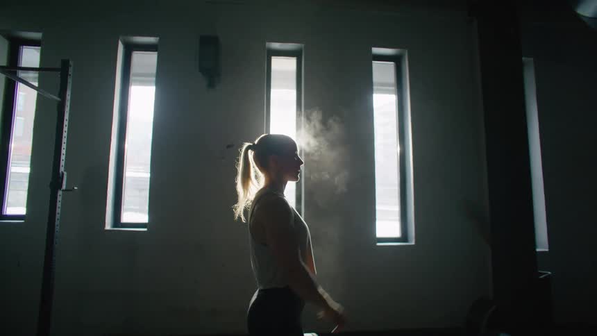 A silhouette of a blonde woman clapping her hands and powder flying upwards