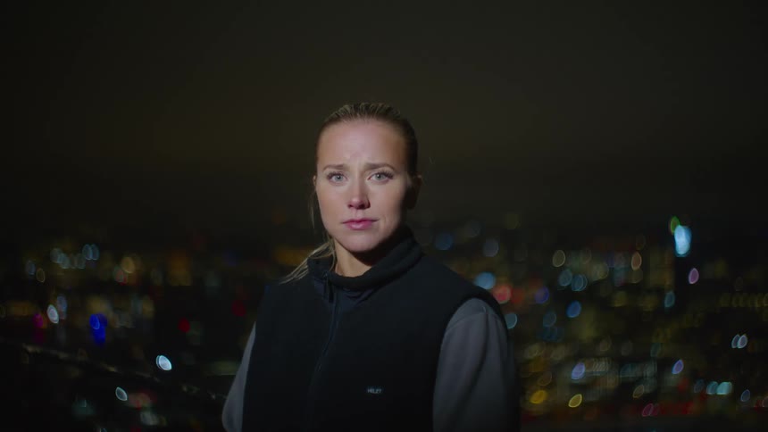 A woman looking while standing in the middle of the street at night