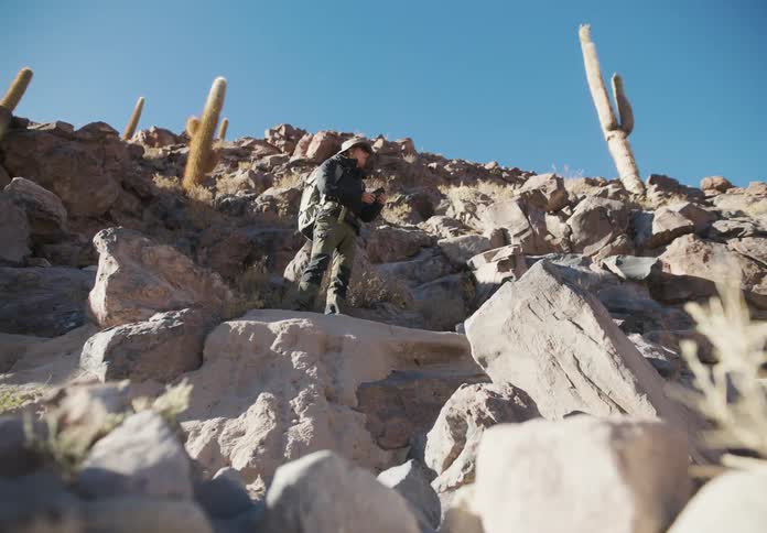 A man hiking on a mountain path with lots of rock laying around
