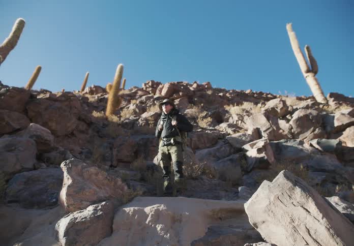A man stands on a flat rocky ledge he looks around surveying the area