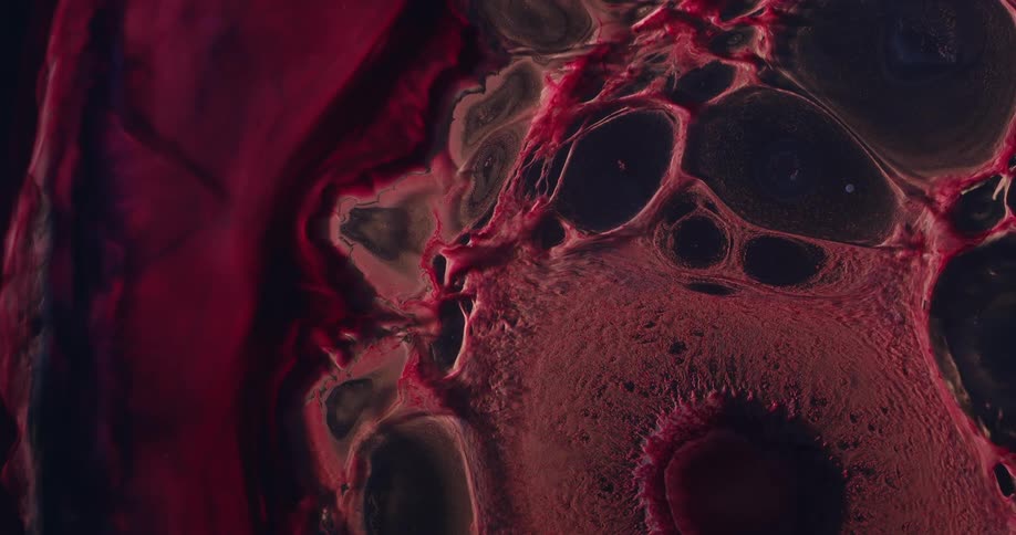 Extreme close up on an abstract reddish fluid expanding