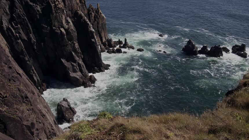 Aerial of sea waves breaking on mountain coast