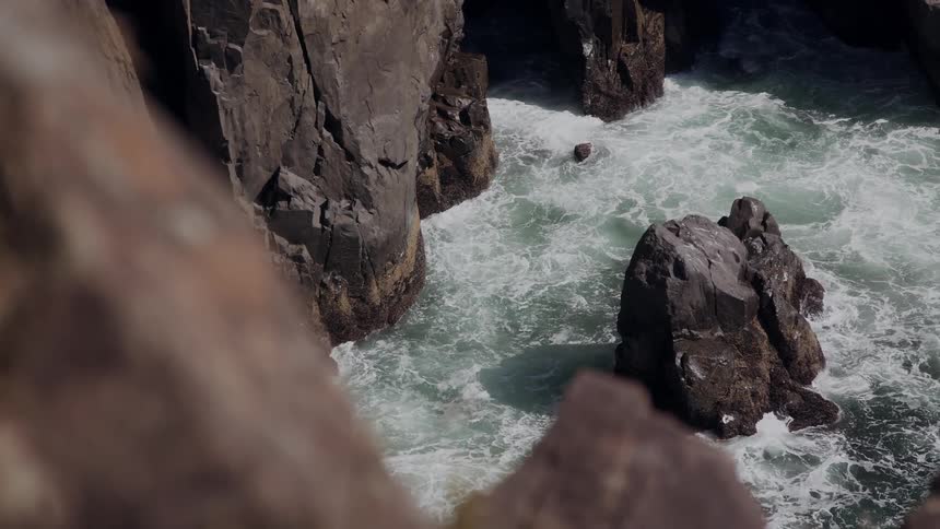 Sea waves breaking on a coast full of high rocks seen from a hill
