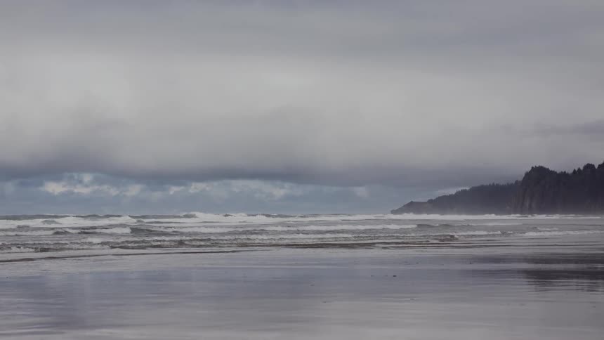 Waves break on the beach during a cloudy day