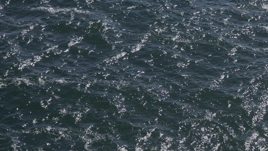 Moving ocean with calm waves and sun reflection during the day