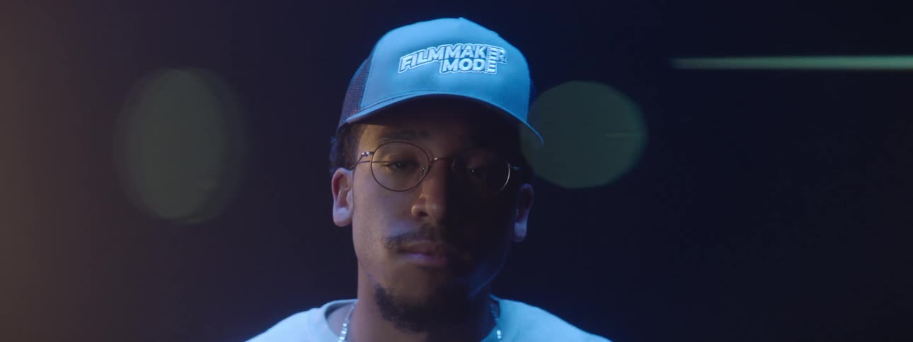 Portrait of a young man adjusting his blue cap indoors