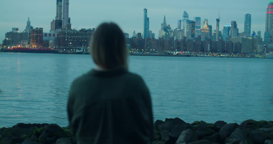 A woman looking over a river towards a cityscape